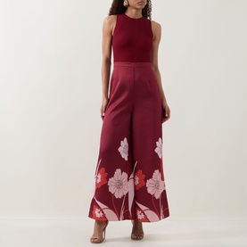 Model wearing Ted Baker Izeny Placement Floral Jumpsuit in dark red, sleeveless with fitted waist and wide-leg floral satin trousers.