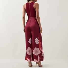 Model wearing Ted Baker Izeny Placement Floral Jumpsuit in dark red, showing rear zip, fitted waist and wide-leg floral print satin trousers.