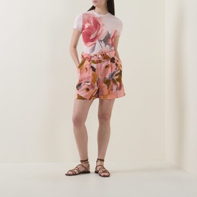 Model wearing Ted Baker Noysa Floral Print Shorts in coral with matching floral tee and brown strappy sandals