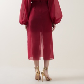 Model wearing Ted Baker Deka Semi-Sheer Layered Skirt in dark red, midi length with semi-sheer overlay, paired with gold strappy heels.
