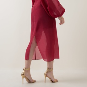 Model wearing Ted Baker Deka Semi-Sheer Dark Red Midi Skirt with layered overlay and rear vent, styled with gold strappy heels