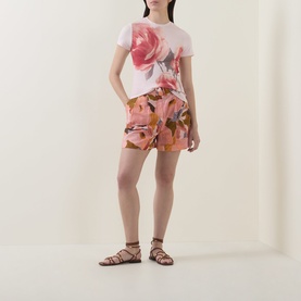 Model wearing Ted Baker Bindii Placement Floral T-Shirt in coral with floral shorts and brown strappy flat sandals.