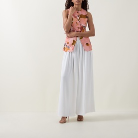 Model wearing Ted Baker Bracci Pleated Wide-Leg Trousers in ivory, high-rise with fluid silhouette, styled with a floral pink top and tan heels.