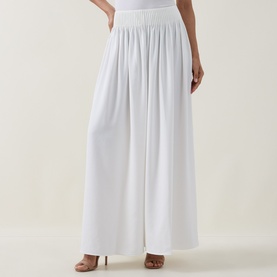 Model wearing Ted Baker Bracci Pleated Wide-Leg Trousers in ivory, high-rise elasticated waistband, fluid wide-leg silhouette, styled with nude heels.