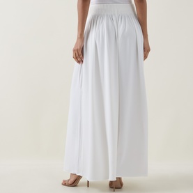 Model wearing Ted Baker Bracci Pleated Wide-Leg Trousers in ivory, showing high-rise elasticated waistband and fluid wide-leg silhouette from behind.