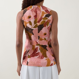 Model wearing Ted Baker Narlla Floral Print Waistcoat in coral, back view, showing fitted waist and floral print. Styled with white trousers.