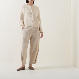 Model wearing Masai Leryntha Knit Cardigan in beige with round neck and ribbed trims, styled with matching tapered trousers and flat shoes.