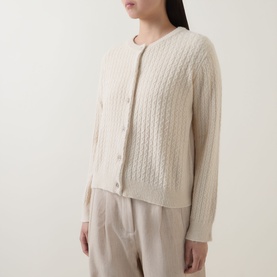 Model wearing Masai Leryntha Knit Cardigan in beige with cable-knit texture, round neck, and button front, styled with wide-leg trousers.