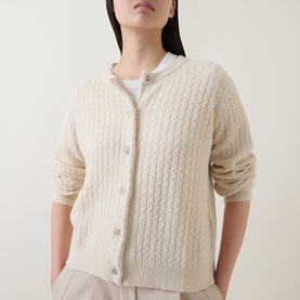 Model wearing Masai Leryntha Knit Cardigan in beige, cable-knit texture, round neck, button front, long sleeves with ribbed trims, styled over white