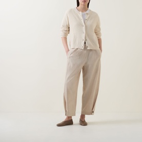 Model wearing Masai Leryntha Knit Cardigan in beige with ribbed trims and dropped shoulders, styled with matching tapered trousers and loafers.