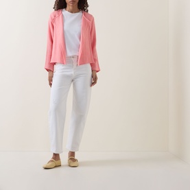 Model wearing pink open-front jacket with white crew-neck tee, white straight-leg trousers, and pale yellow flat shoes.