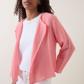 Model wearing pink open-front knit cardigan styled with a white crew-neck tee and white trousers