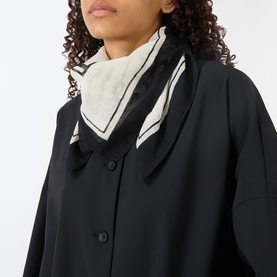 Model with Masai Avioneth Printed Scarf in black, tied at neck, square shape with contrast border detailing in cream and black