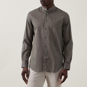 Model wearing Paul Smith blue striped cotton-silk casual shirt with mandarin collar and button placket, styled with light trousers.