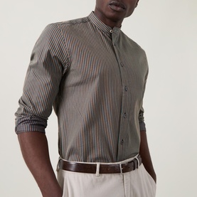 Model wearing Paul Smith blue striped cotton-silk casual shirt with grandad collar, styled with light trousers and brown leather belt