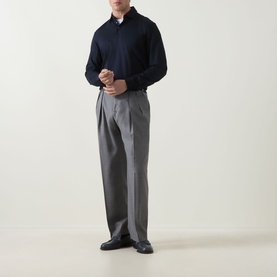 Model wearing Paul Smith Double Pleat Wool Trousers in grey, styled with a navy polo shirt and black leather shoes.