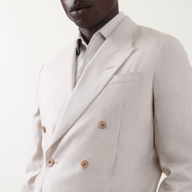 Model wearing Paul Smith white linen-wool double-breasted blazer with tan buttons and pocket square, styled with a grey shirt.