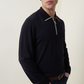 Model wearing Paul Smith blue merino wool polo knit with contrast green zip detail at collar, paired with brown leather belt.