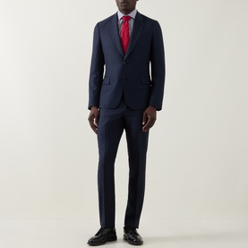 Model wearing Paul Smith navy wool suit with red tie and white shirt, styled with black Oxford shoes.