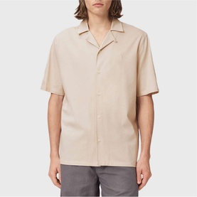 Model wearing All Saints birch white short sleeve camp collar shirt, styled with grey trousers.