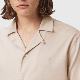 Model wearing All Saints birch white short sleeve camp collar shirt with embroidered logo detail at chest.