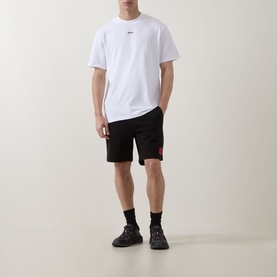 Model wearing Hugo white crew neck T-shirt with black shorts and chunky trainers.