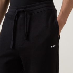 Model wearing Hugo black cotton sweatpants with drawstring waist, side pockets and small white logo print on left leg