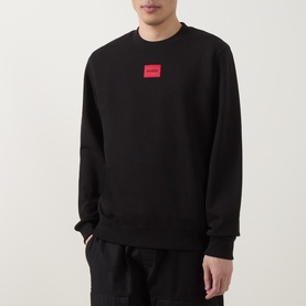 Model wearing Hugo Diragol Logo Sweatshirt in black with red logo patch, crew neck, paired with black trousers.