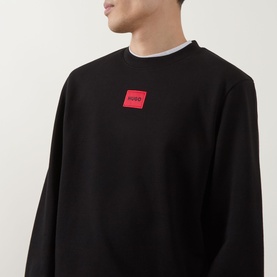 Model wearing Hugo Diragol Logo Sweatshirt in black, crew neck with red logo patch on chest, styled with white crew neck underneath.