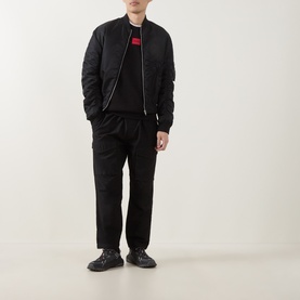 Model wearing Hugo Diragol Logo Sweatshirt in black with red logo detail, styled with black bomber jacket and black trousers.