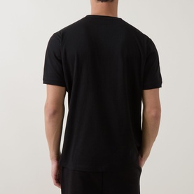 Model wearing Hugo black cotton T-shirt, rear view, with matching black trousers.