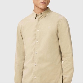 Model wearing All Saints cord brown long-sleeve button-down shirt with small embroidered logo at chest.