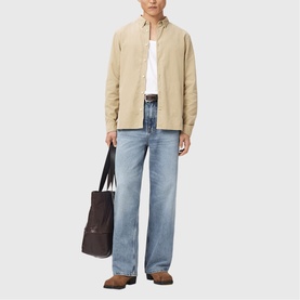 Model wearing All Saints cord brown overshirt, styled with white tee, light wash jeans, and carrying a dark brown tote bag.
