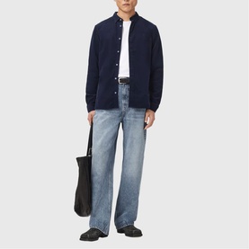 Model wearing All Saints sapphire blue shirt jacket over white shirt, styled with light wash wide-leg jeans and black loafers, carrying black tote