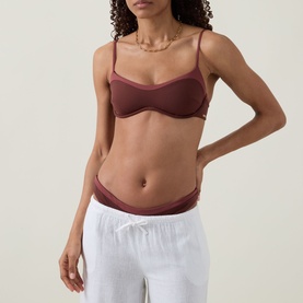 Model wearing Tala Deep Rust bikini top with thin straps, styled with white drawstring trousers.