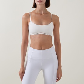 Model wearing Tala DayFlex Strappy Back Sports Bra in ivory with scoop neckline and adjustable straps, styled with matching ivory leggings.