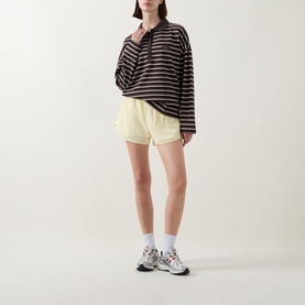Model wearing Tala Striped Logo Rugby Top in Mocha Brown with yellow shorts and white trainer socks.
