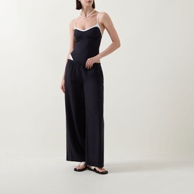 Model wearing Tala Resort Drawstring Flared Trousers in Shadow Black, styled with a white-trim cami top and strappy sandals.
