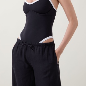 Model wearing Tala Resort Drawstring Flared Trousers in Shadow Black with drawstring waist, styled with a black and white bodysuit.