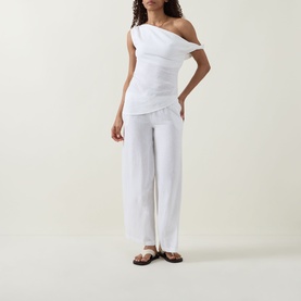 Model wearing Tala Soft Wide Leg Trousers in ivory linen-viscose blend, styled with white one-shoulder top and brown flat sandals.