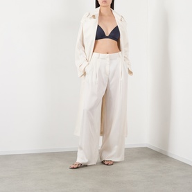 Model wearing The Frankie Shop navy triangle bralette top, styled with cream wide-leg trousers and a matching longline shirt.