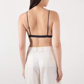 Model wearing The Frankie Shop navy viscose bralette top, back view, styled with white wide-leg trousers