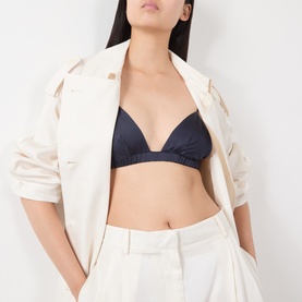 Model wearing The Frankie Shop navy viscose bralette top, styled with an open cream jacket and white wide-leg trousers.
