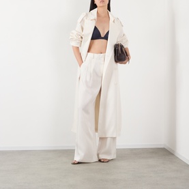 Model wearing The Frankie Shop navy bralette top with cream wide-leg trousers and long coat, carrying a small brown bag.