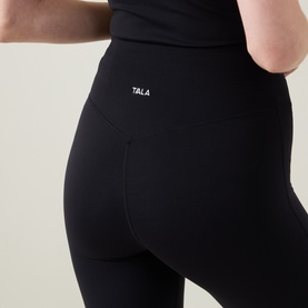 Model wearing Tala Shadow Black high-waist leggings, close-up of hip and pocket detail in nylon-lycra fabric.