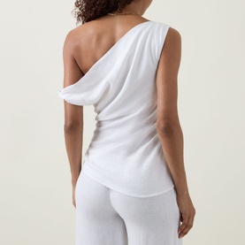 Model wearing Tala ivory one-shoulder draped linen-blend top, styled with matching ivory wide-leg trousers, back view.