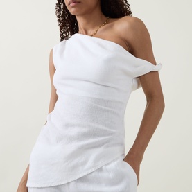 Model wearing Tala ivory one-shoulder linen-viscose top, styled with a gold chain necklace