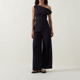 Model wearing Tala Shadow Black one-shoulder linen-viscose top with wide-leg trousers and flat sandals