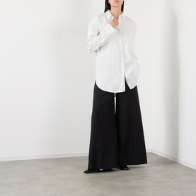 Model wearing The Frankie Shop white viscose shirt with wide-leg black trousers, full-length relaxed silhouette