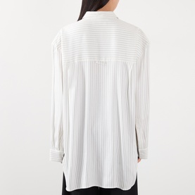 Model wearing The Frankie Shop shirt in white and black stripe, 100% viscose, shown from the back with long sleeves and relaxed fit.
